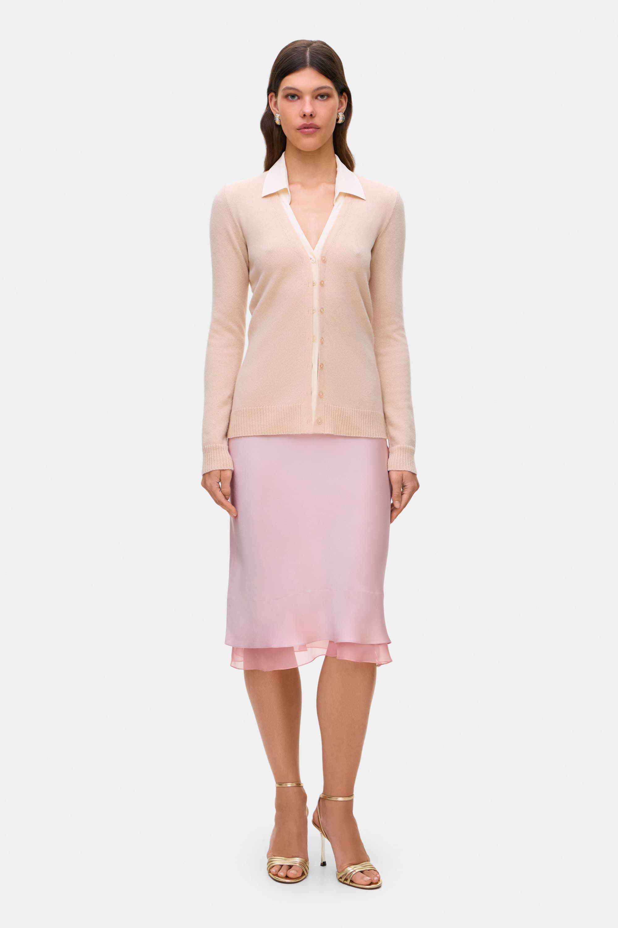 Woman wearing a beige Daniella cardigan and powder pink Elina skirt on a white background, front view