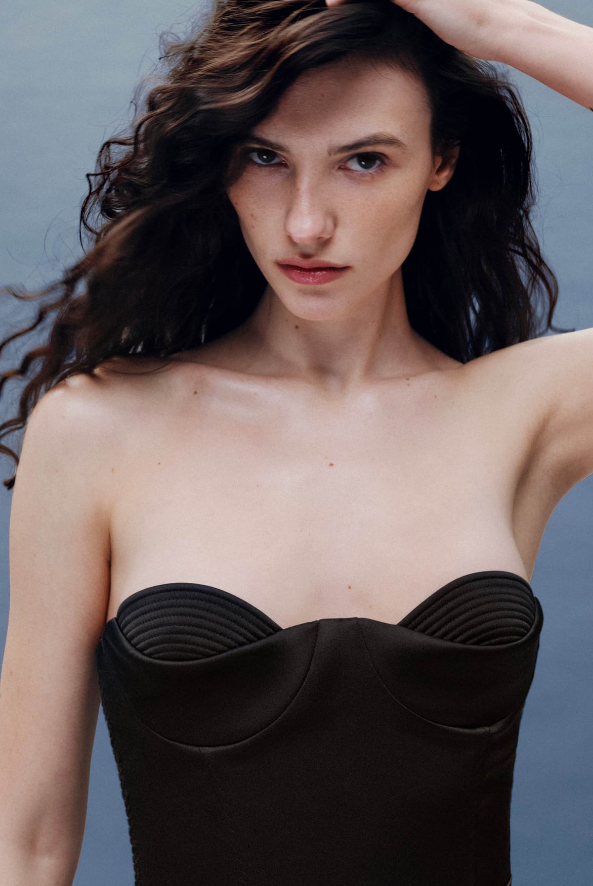 Woman wearing a black Raya corset against a gray background