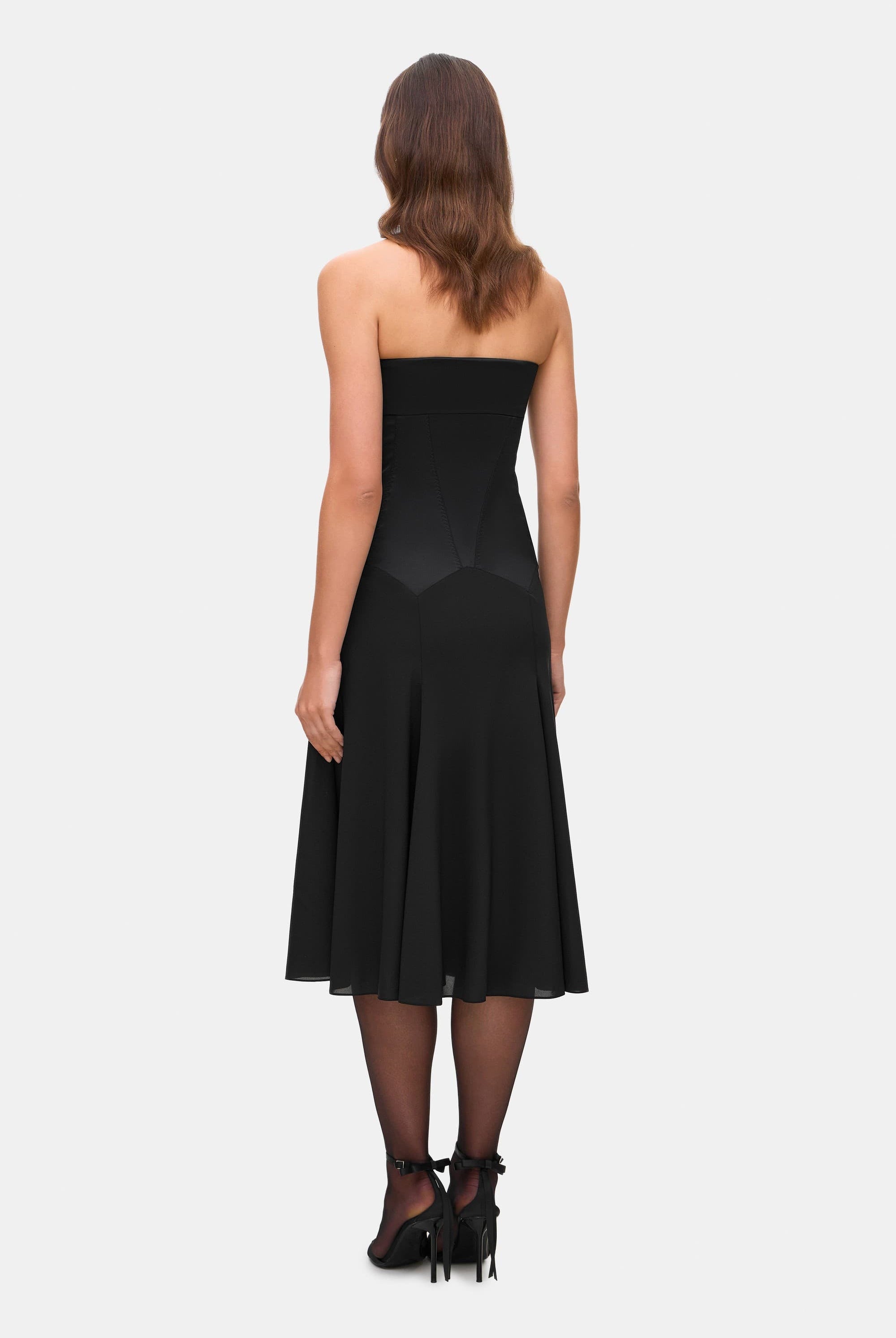 Woman wearing a black strapless Ariella dress on a white background, back view