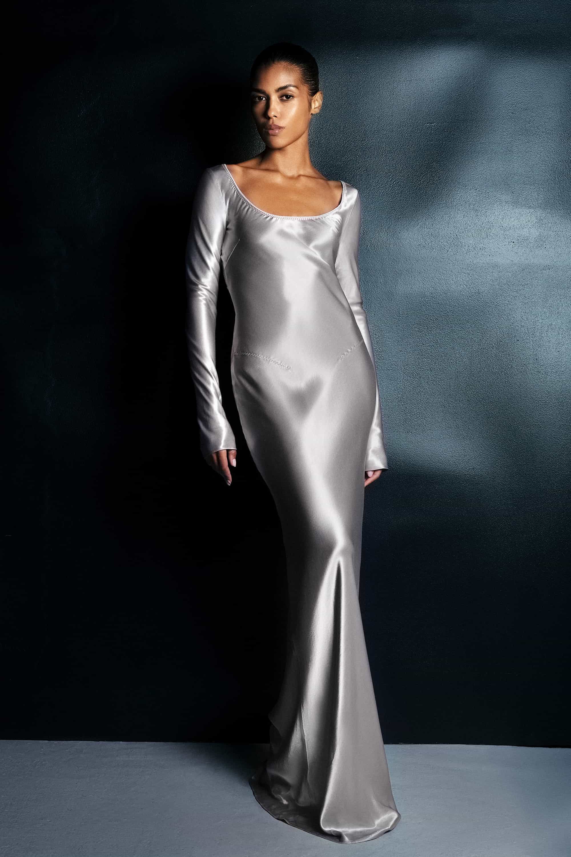Woman wearing a silver Margit dress against a dark background, front view