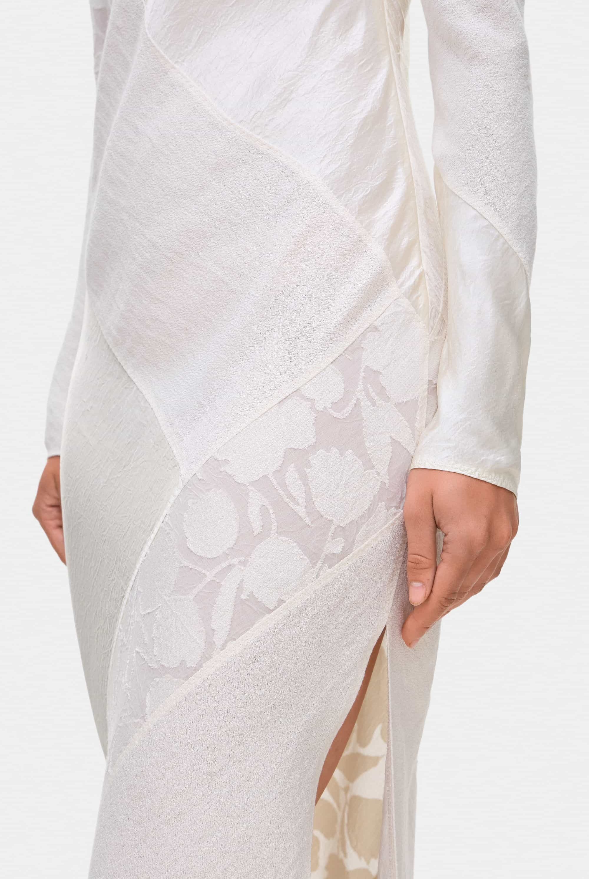 Woman wearing a ivory long-sleeve off-shoulder Santa dress with floral patterns on a white background, side details view