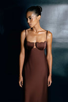 Woman wearing a brown Tulip dress with a textured bodice against a dark background