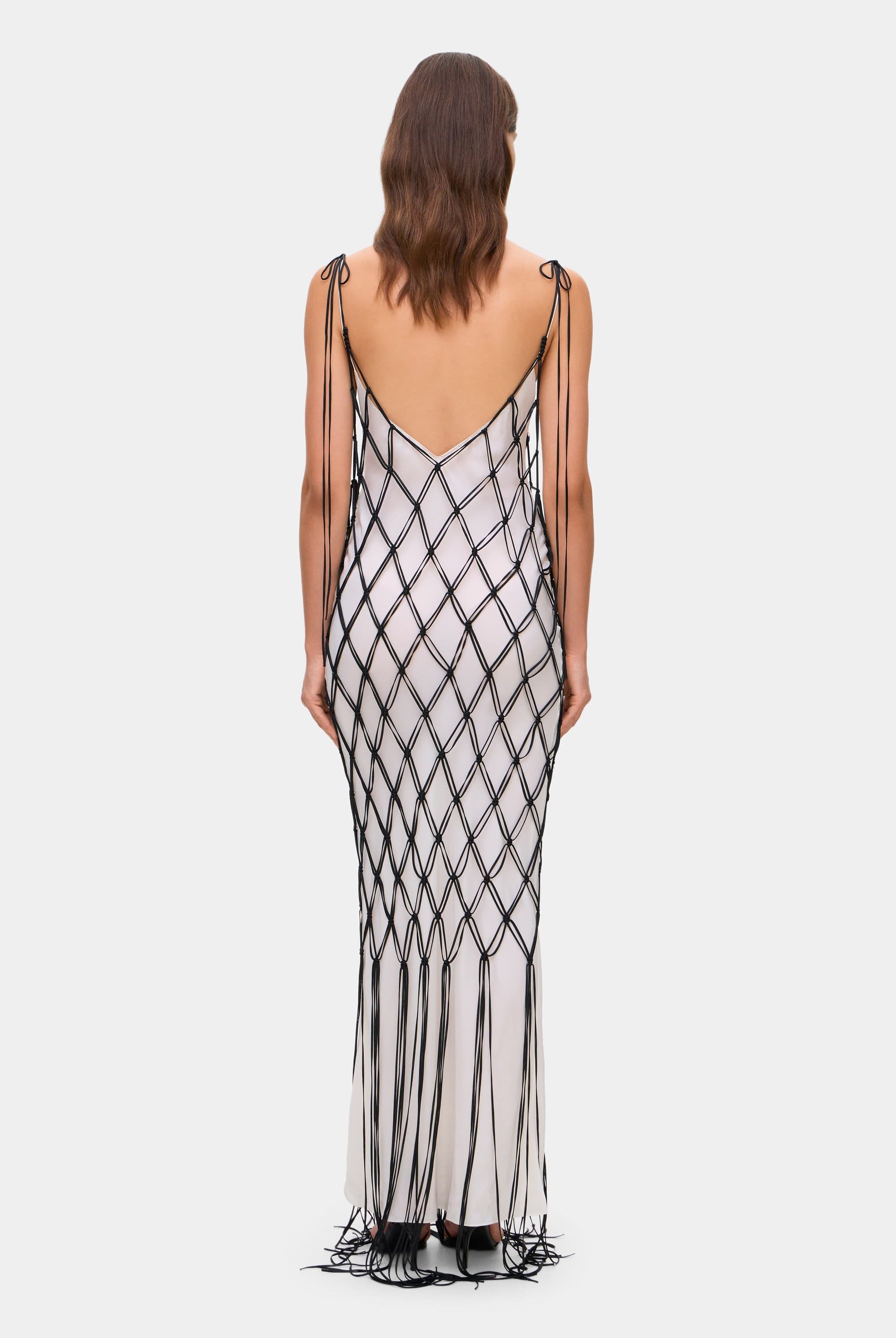 Woman wearing a ivory and black netted patterned with thin straps Helena dress on a white background, back view