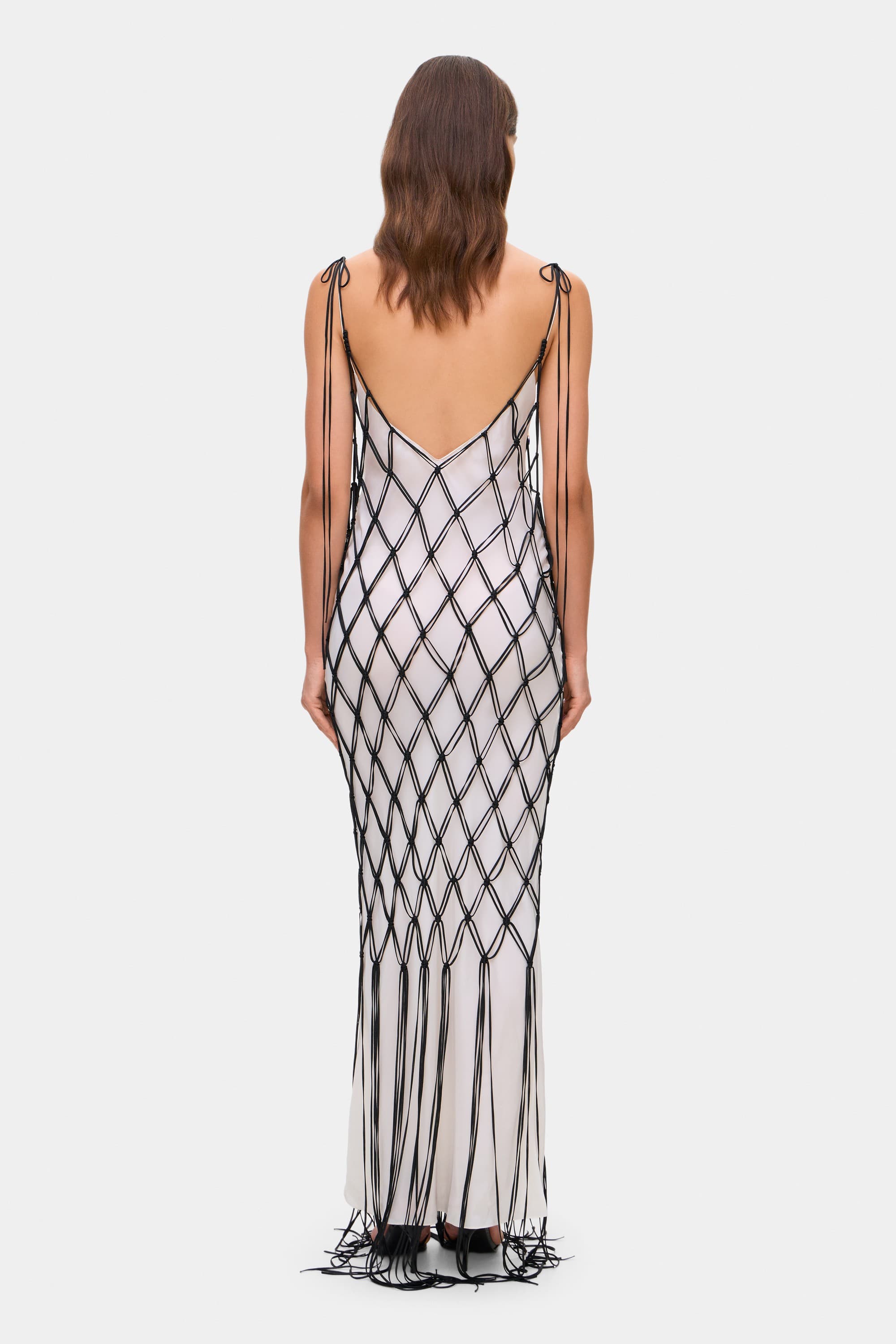 Woman wearing a ivory and black netted patterned with thin straps Helena dress on a white background, back view