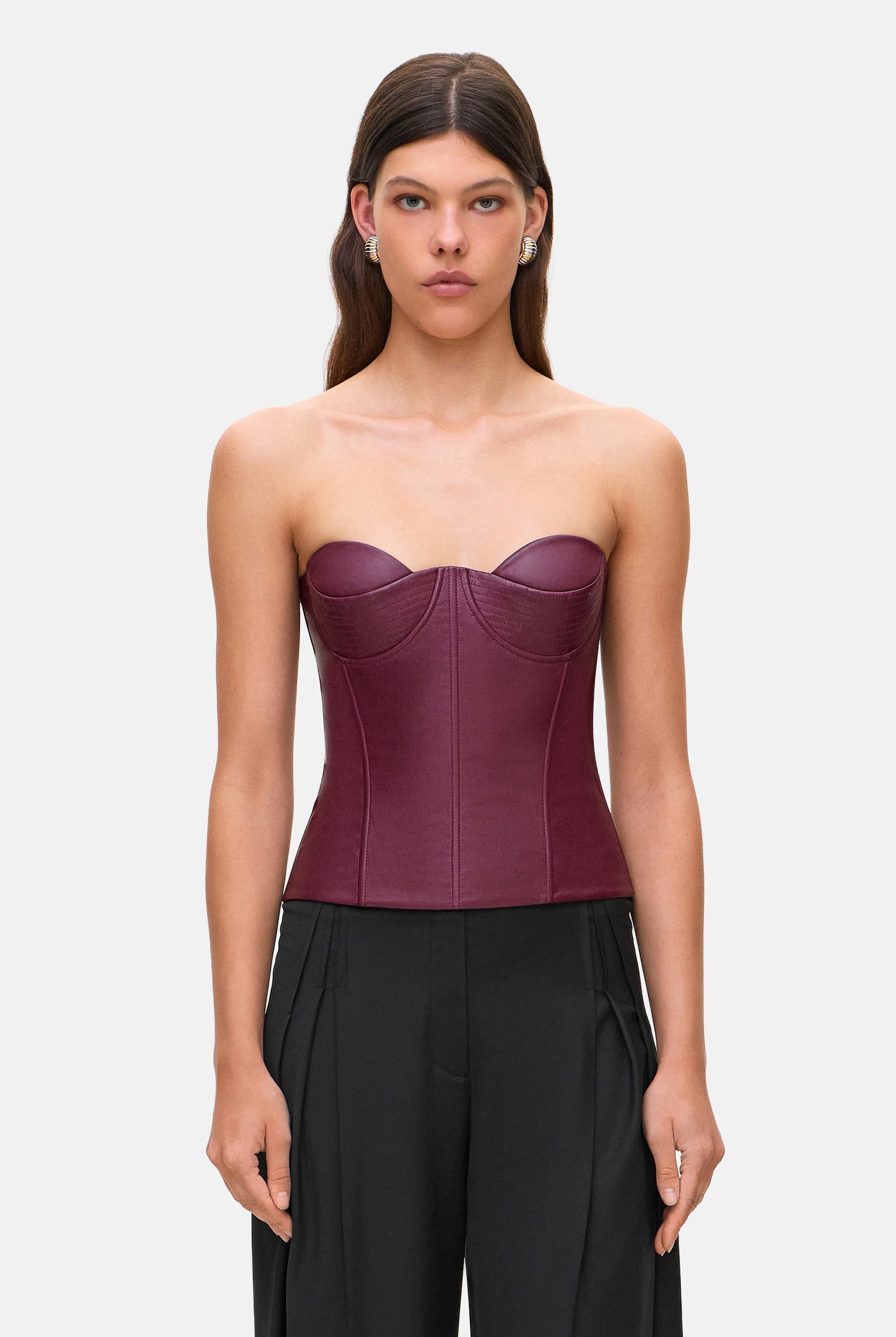 Woman wearing a strapless burgundy Susana corset and black pants on a white background, front view