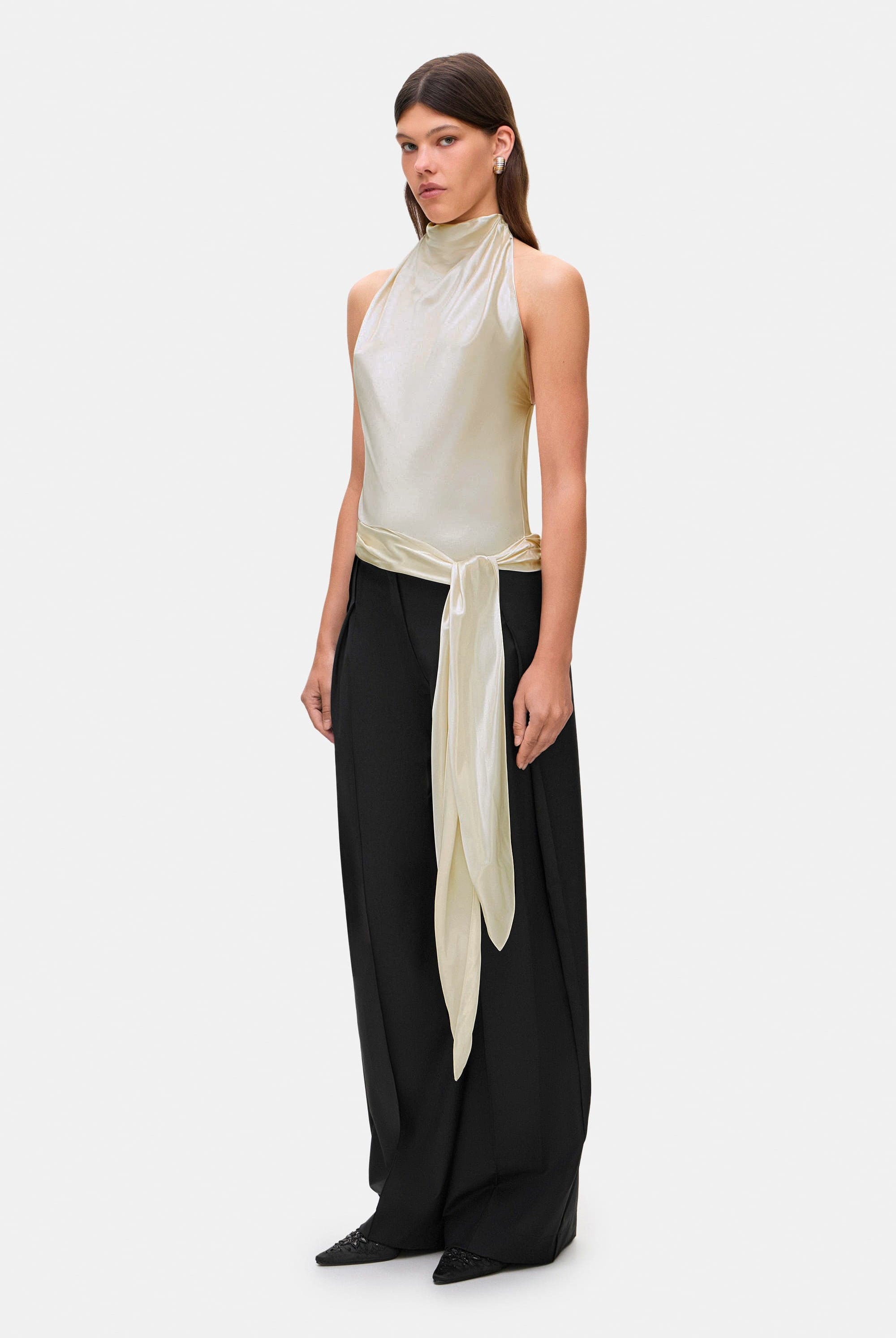 Woman wearing a ivory sleeveless Soma top and black wide-leg pants, side view