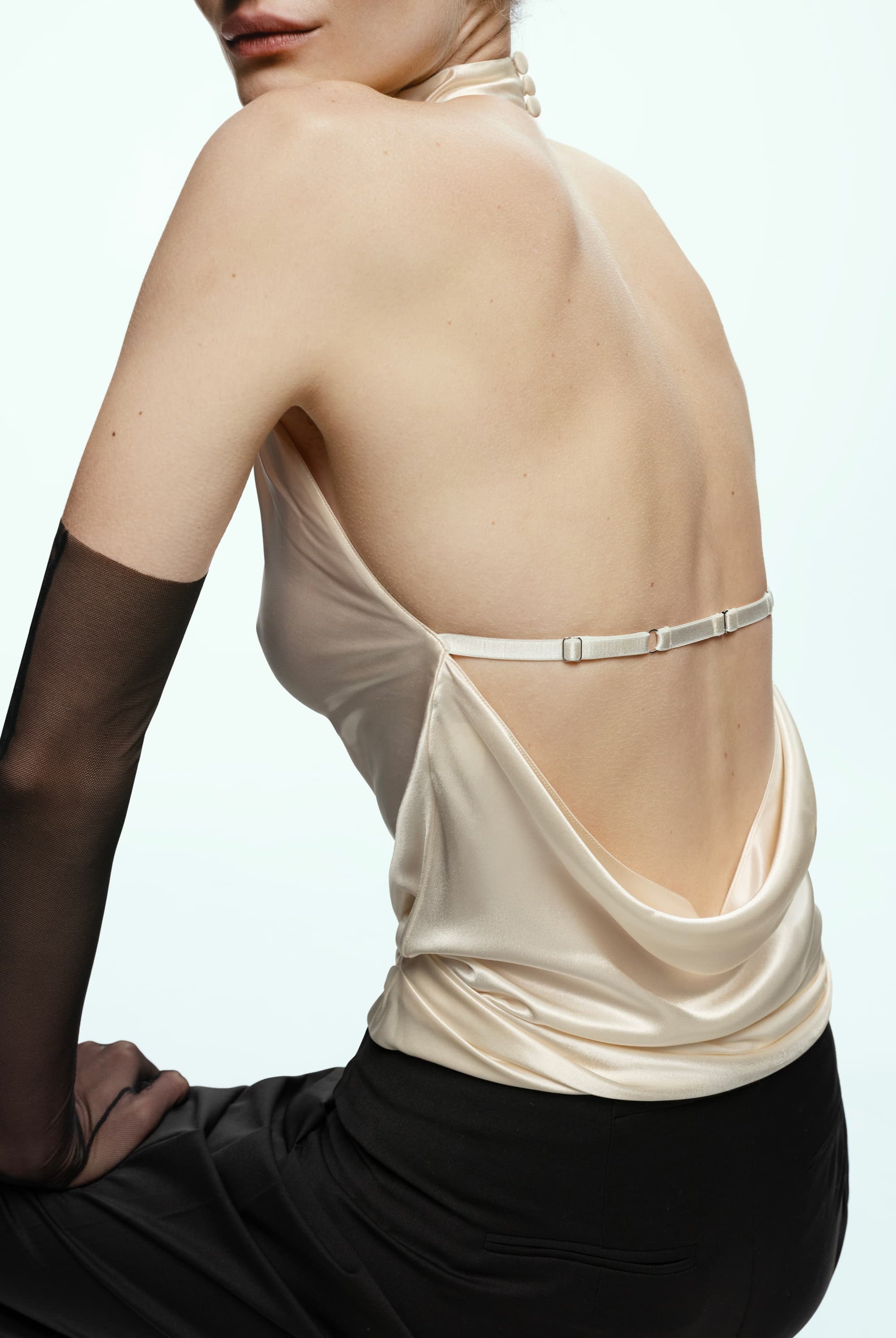 Ivory Soma top with open back and black stockings on a plain background