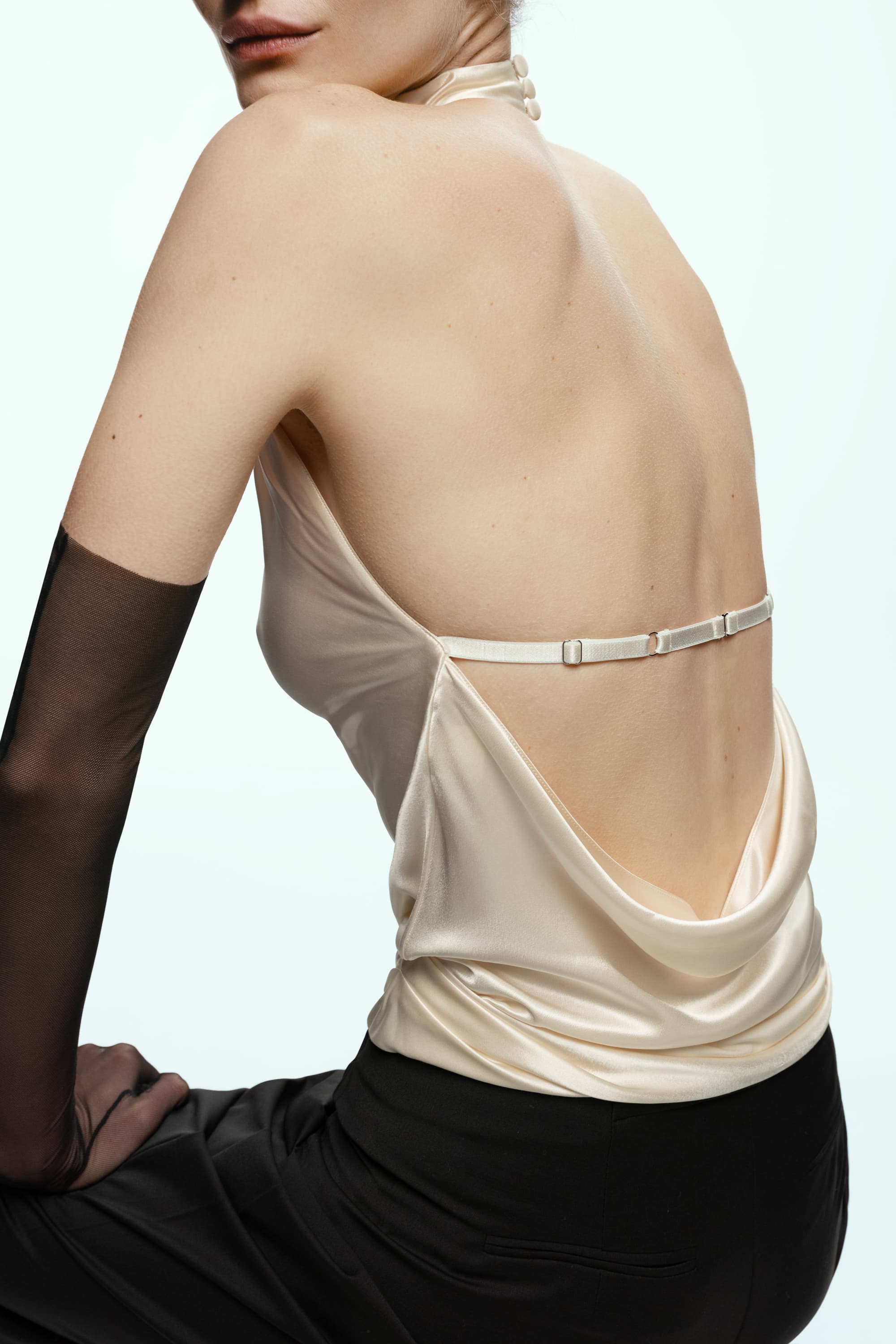 Ivory Soma top with open back and black stockings on a plain background