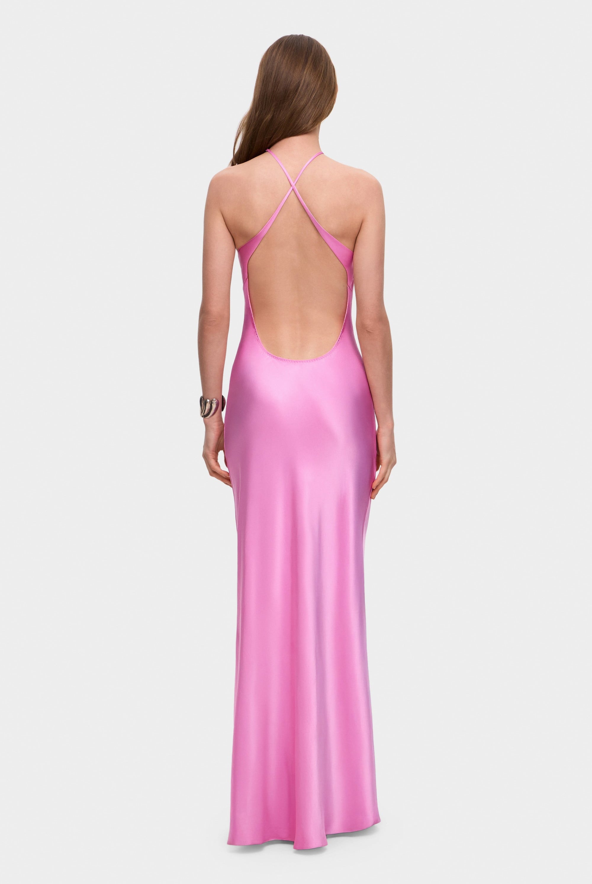 Woman wearing a pink halter neck Angela dress with open back on a white background, back view