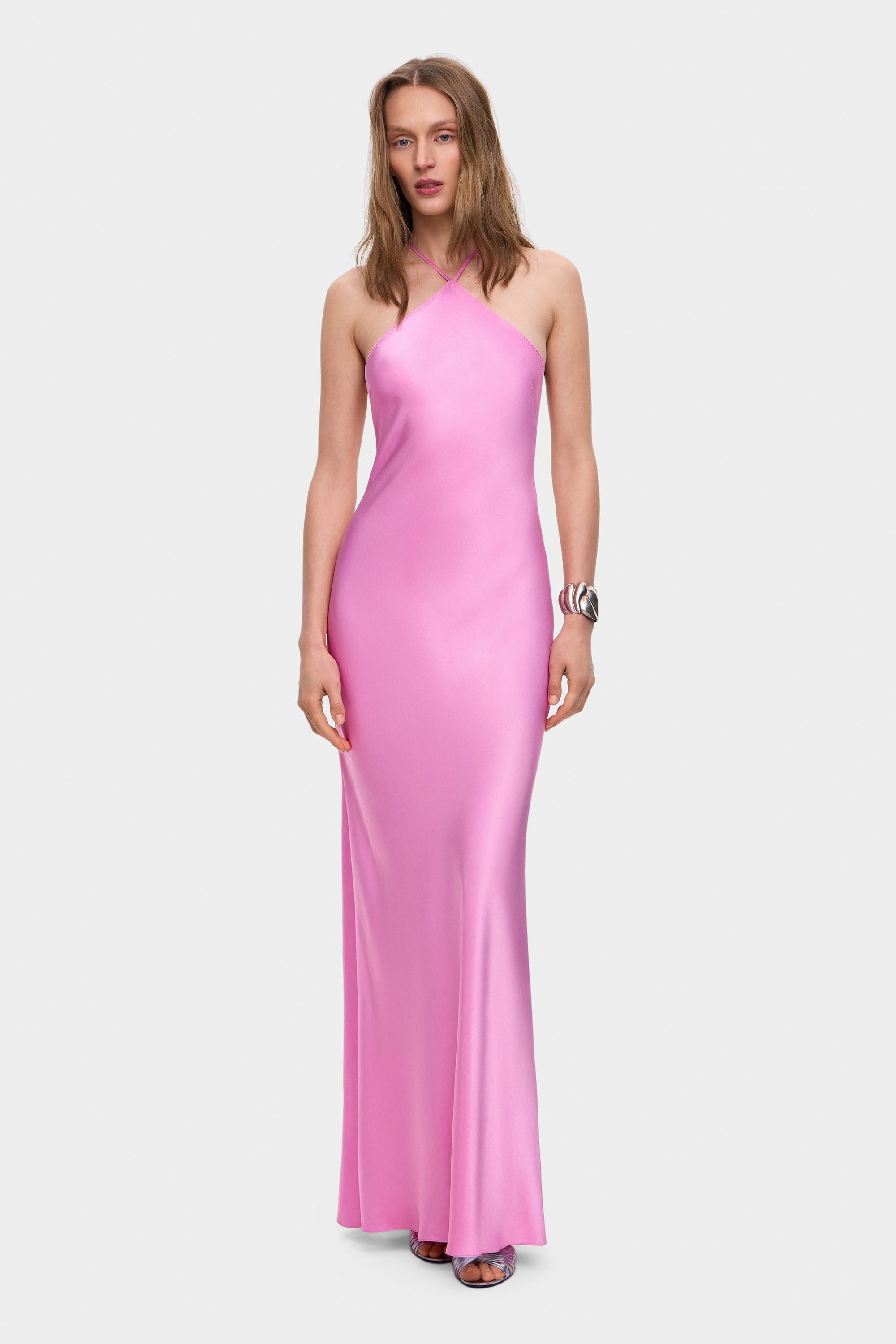 Woman wearing a pink halter neck Angela dress on a white background, front view