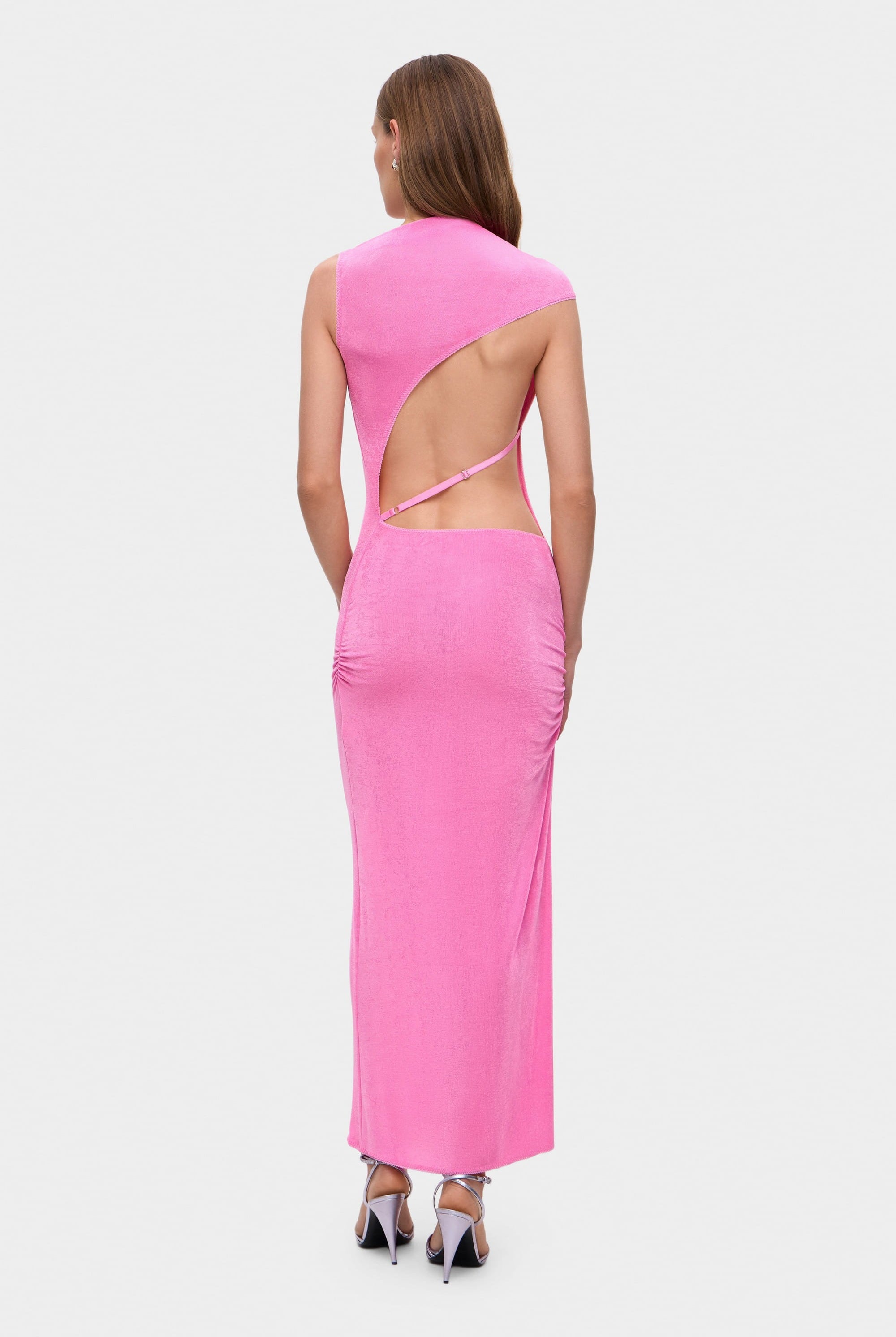 Woman wearing a pink sleeveless Aya dress with cut-out design on a white background, back view