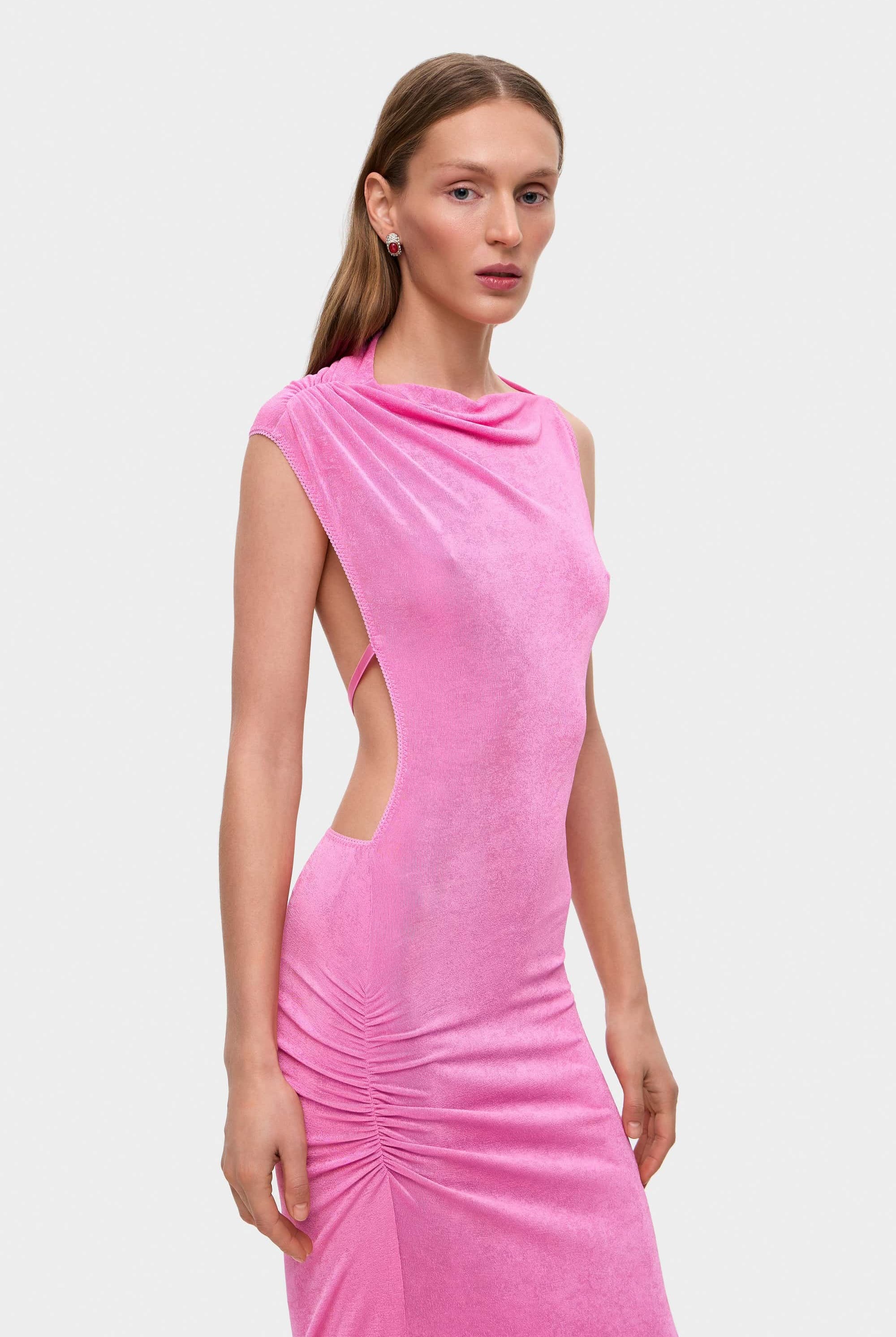 Woman wearing a pink sleeveless Aya dress with cut-out design on a white background, detail side view