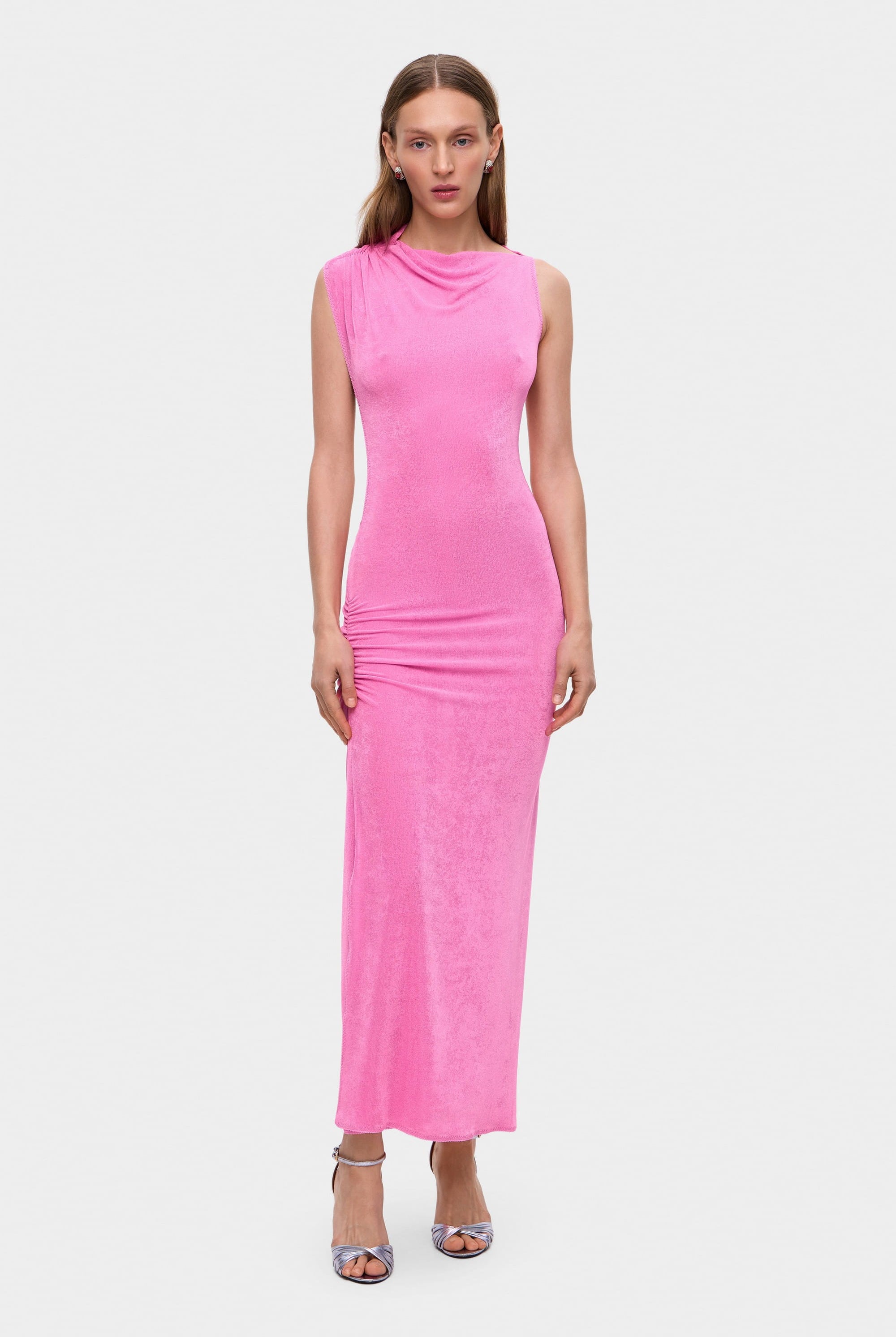 Woman wearing a pink sleeveless Aya dress with cut-out design on a white background, front view