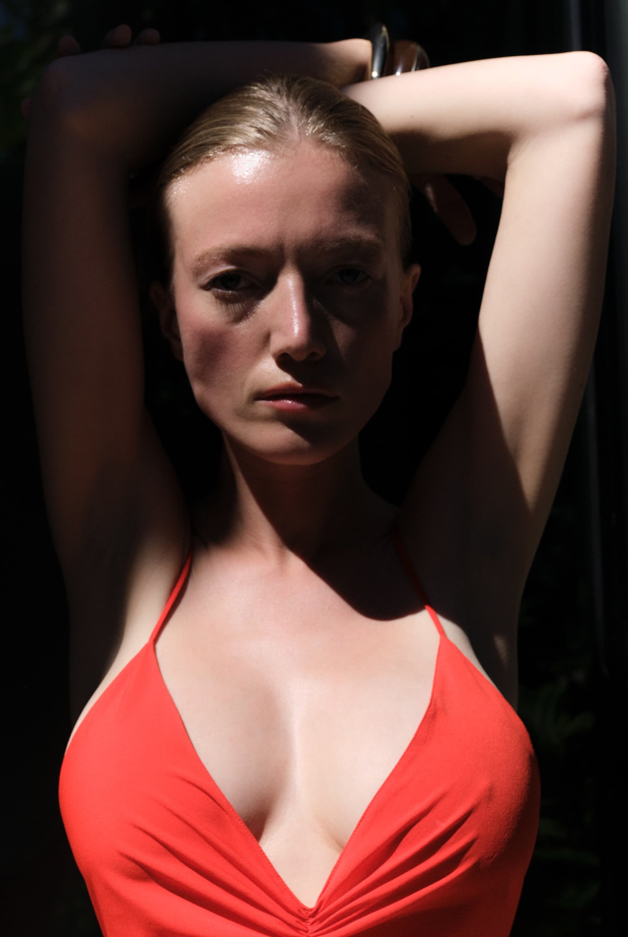 Woman in a coral Eliana dress posing against a dark background, detail front view