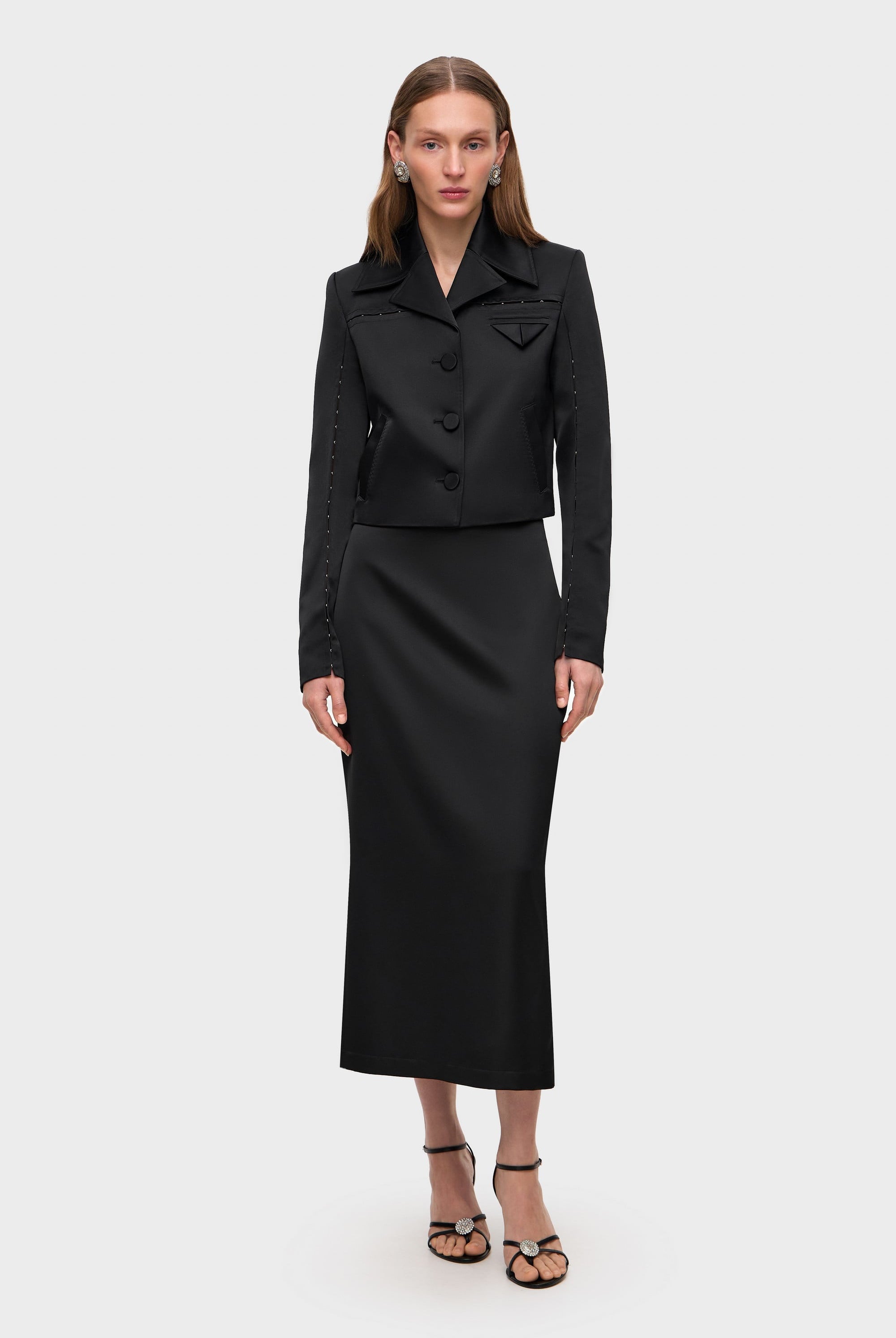 Woman wearing a black Kaya skirt on a white background, front view