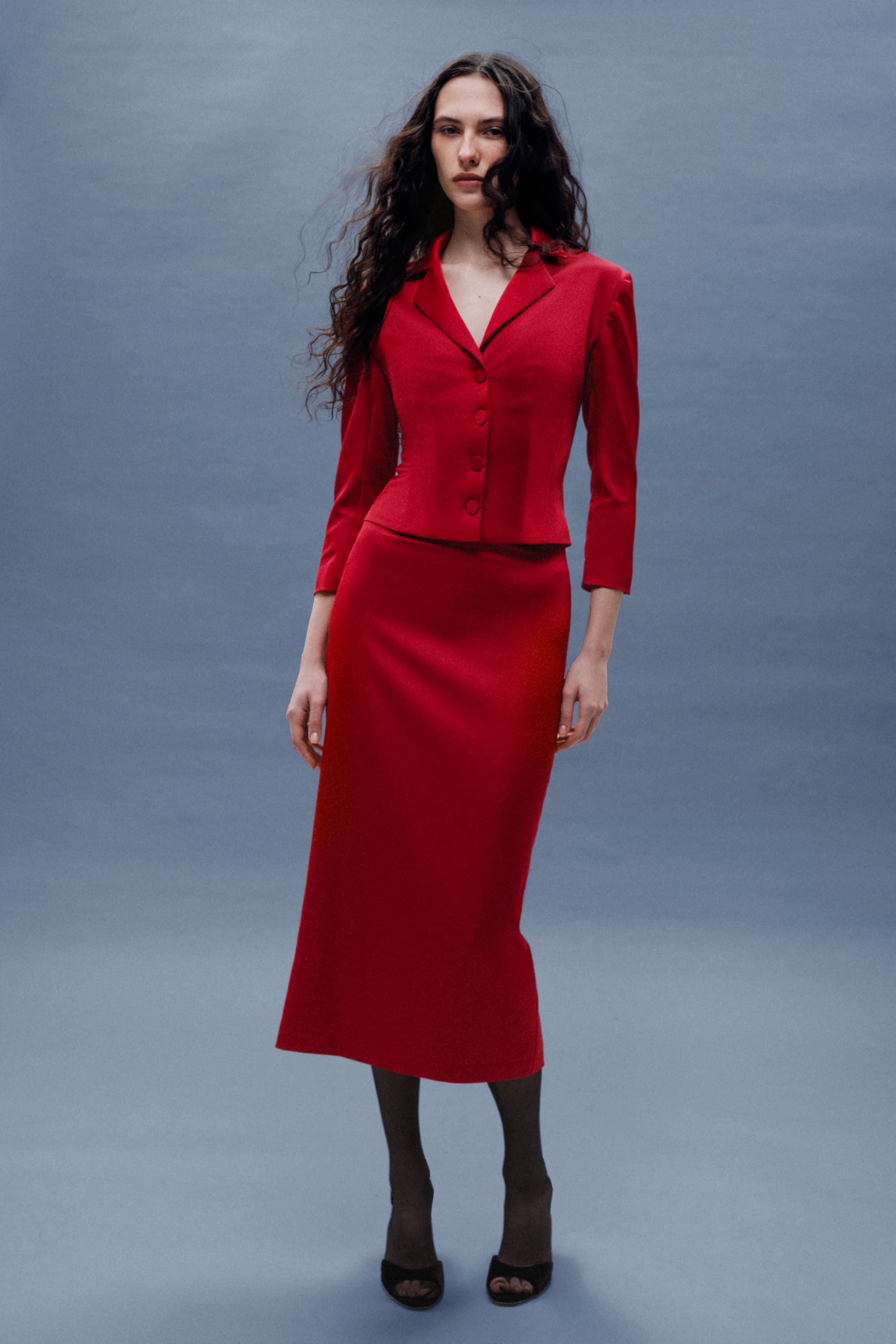 Woman wearing a red Kaya skirt on a grey background, front view