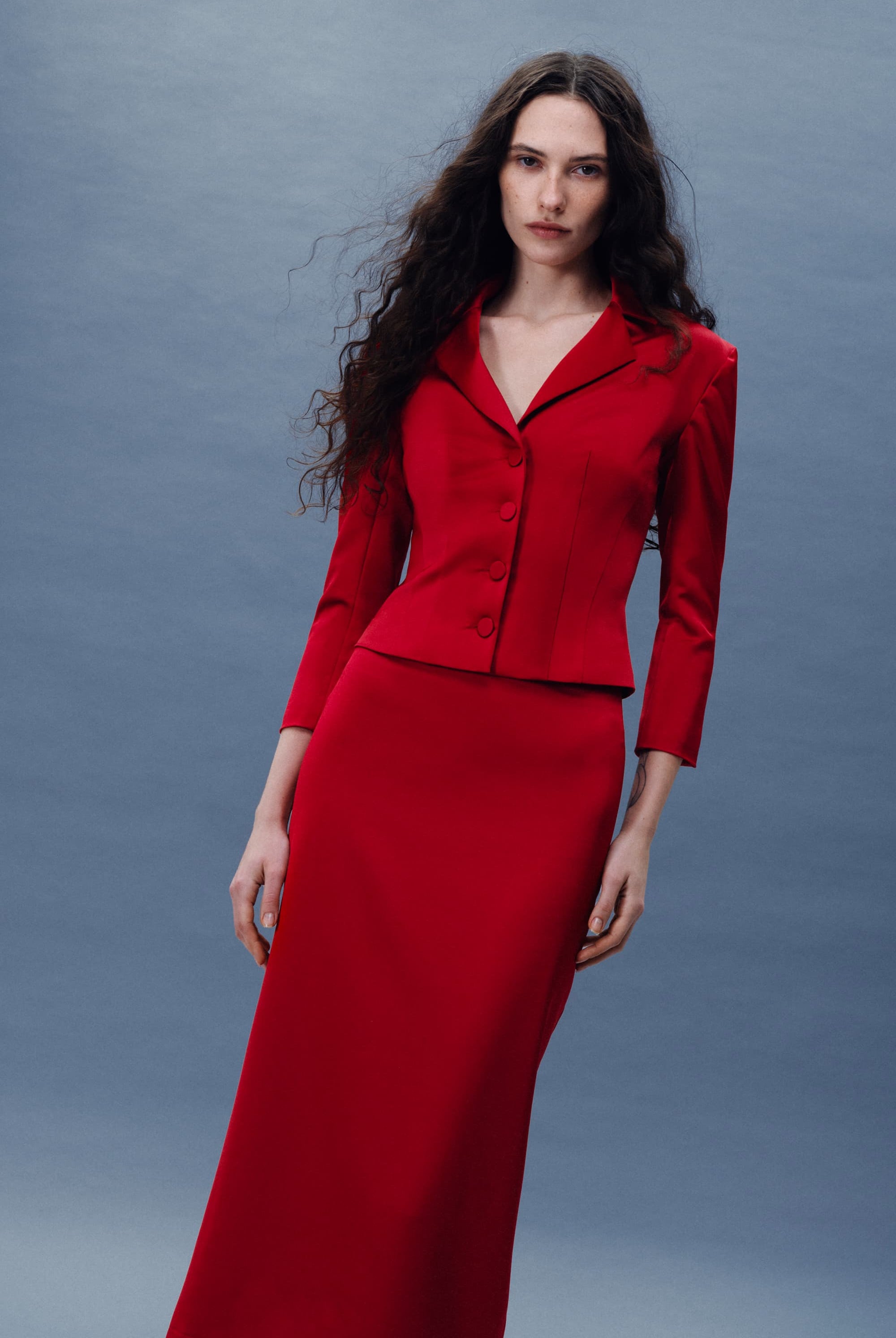 Woman wearing a red Giada jacket against a gray background