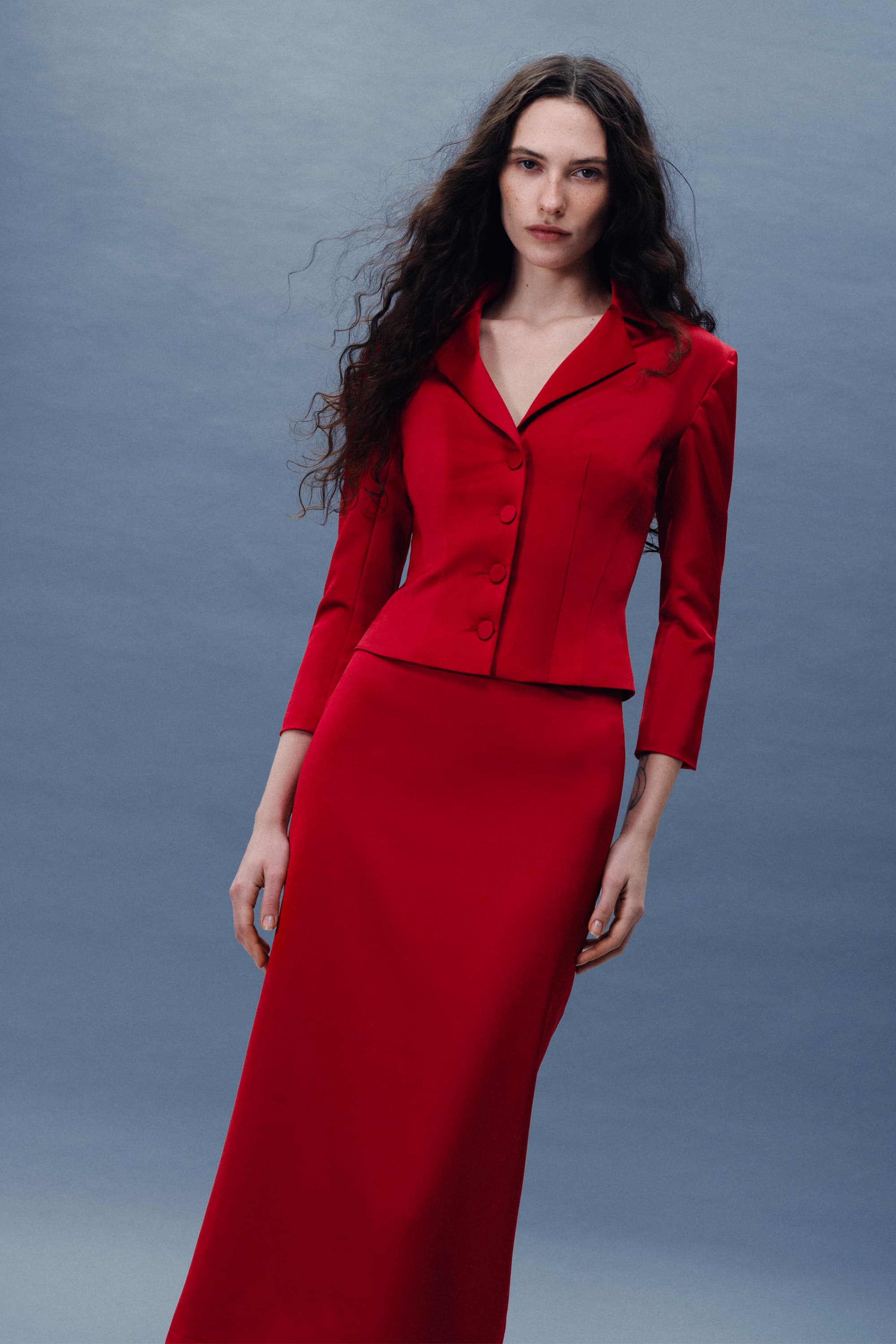 Woman wearing a red Giada jacket against a gray background