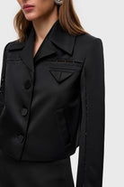 Woman wearing a black Nika jacket on a white background, details side view