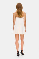 Model in loose Tonia mini dress with tulip-shaped decorated cups and straps tied into bows back view