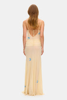 Model in Zoe maxi dress with decorative scarf at the hips, featuring embroidery elements throughout the dress back view