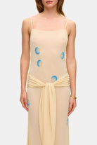 Model in Zoe maxi dress with decorative scarf at the hips, featuring embroidery elements throughout the dress front details view