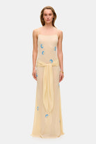 Model in Zoe maxi dress with decorative scarf at the hips, featuring embroidery elements throughout the dress front view