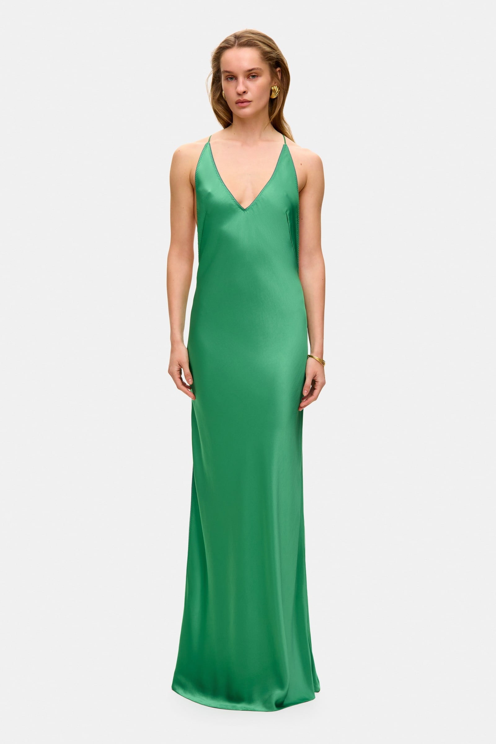 Model in open back maxi Justina dress with flowing design and a slit front view