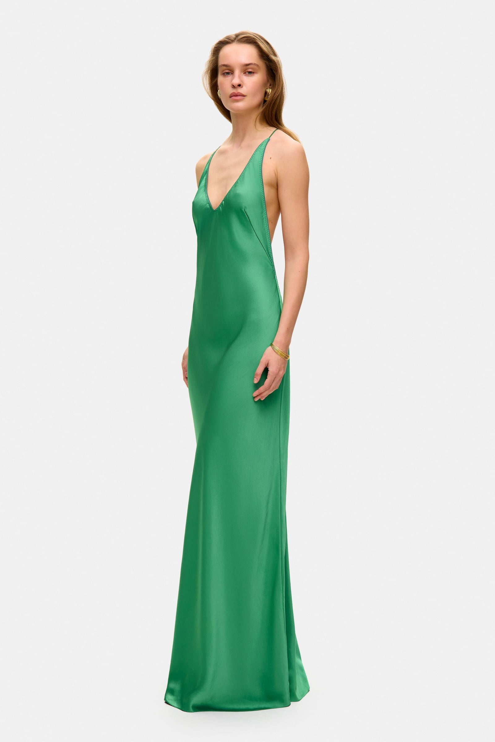 Model in open back maxi Justina dress with flowing design and a slit side view