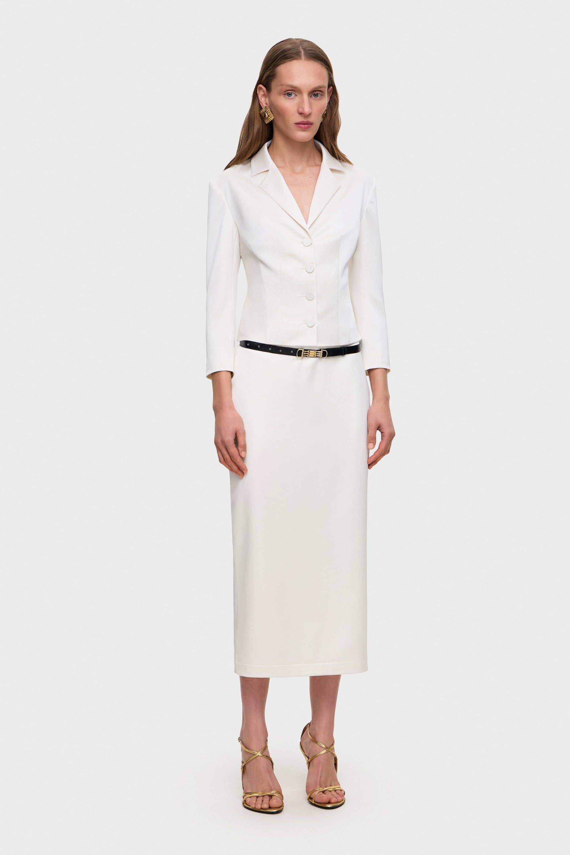 Woman wearing a white Giada jacket and Kaya skirt with a belt on a white background, front view