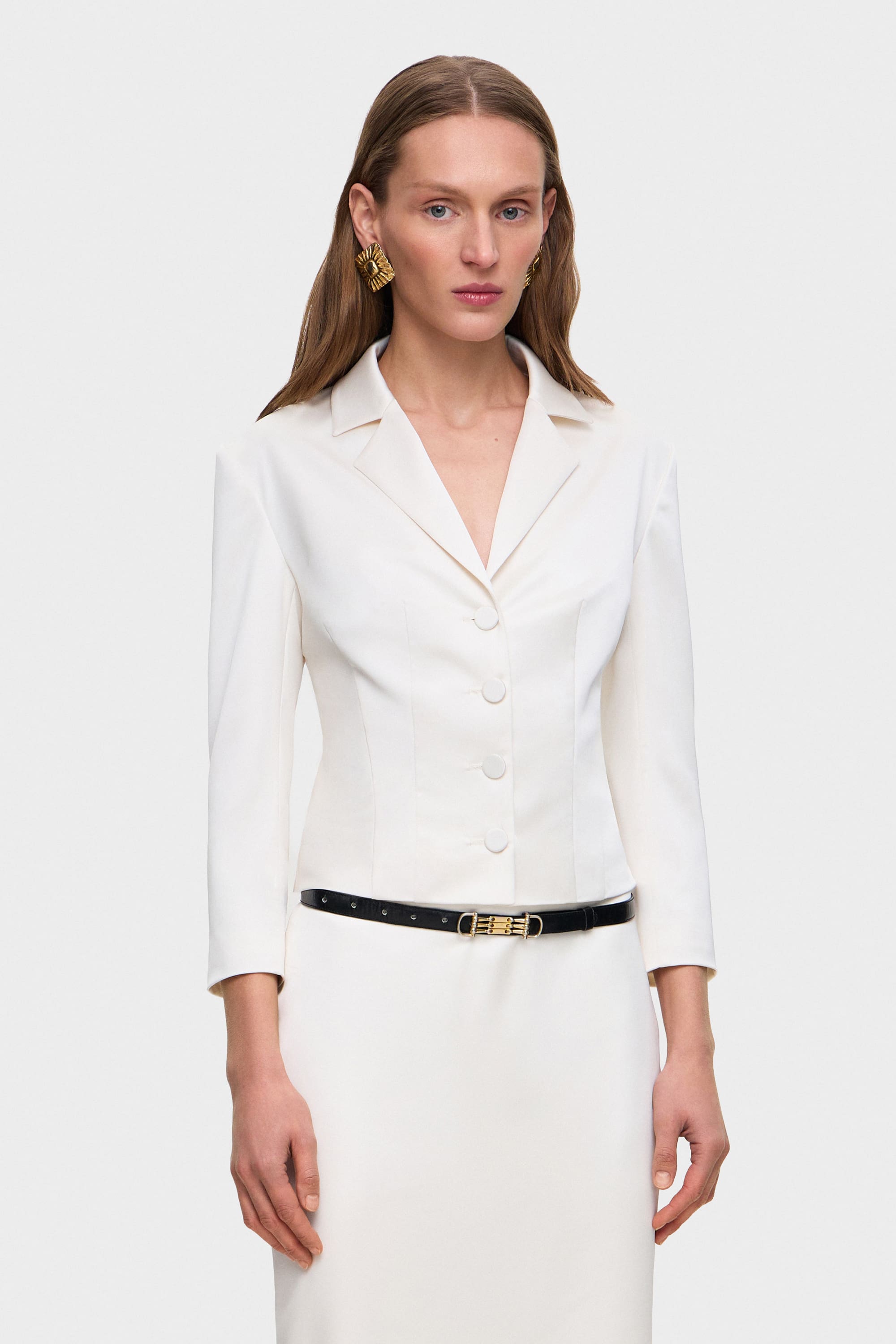 Woman wearing a white Giada jacket with a black belt on a white background, front view