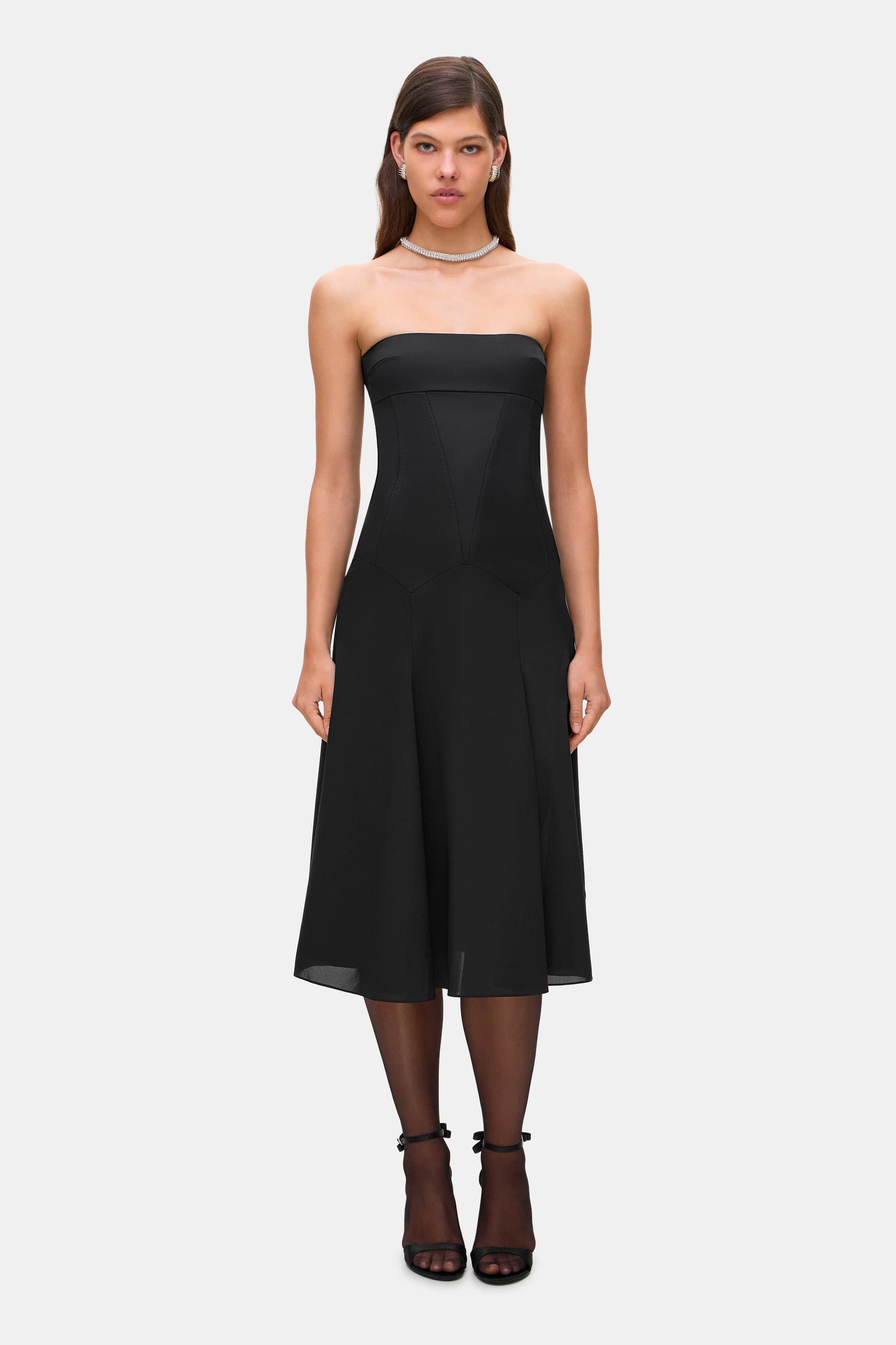 Woman wearing a black strapless Ariella dress on a white background, front view