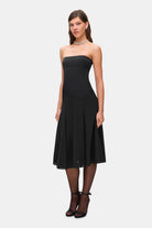 Woman wearing a black strapless Ariella dress on a white background, side view