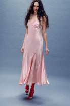 Woman wearing a pink Liza dress with a plain background
