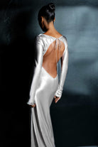 Woman wearing a silver Margit dress against a dark background, back view