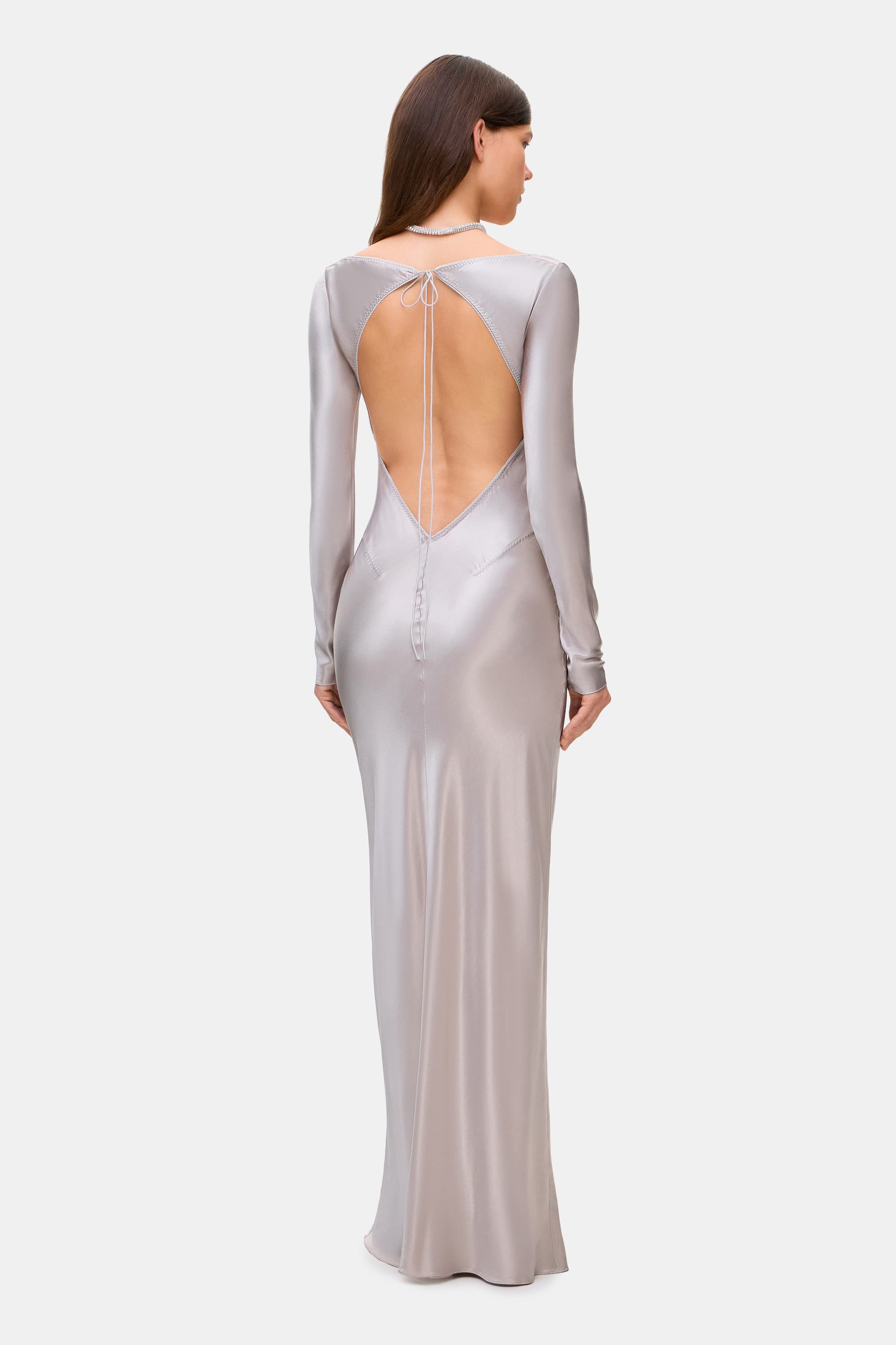 Woman wearing a silver long-sleeve Margit dress on a white background, back view