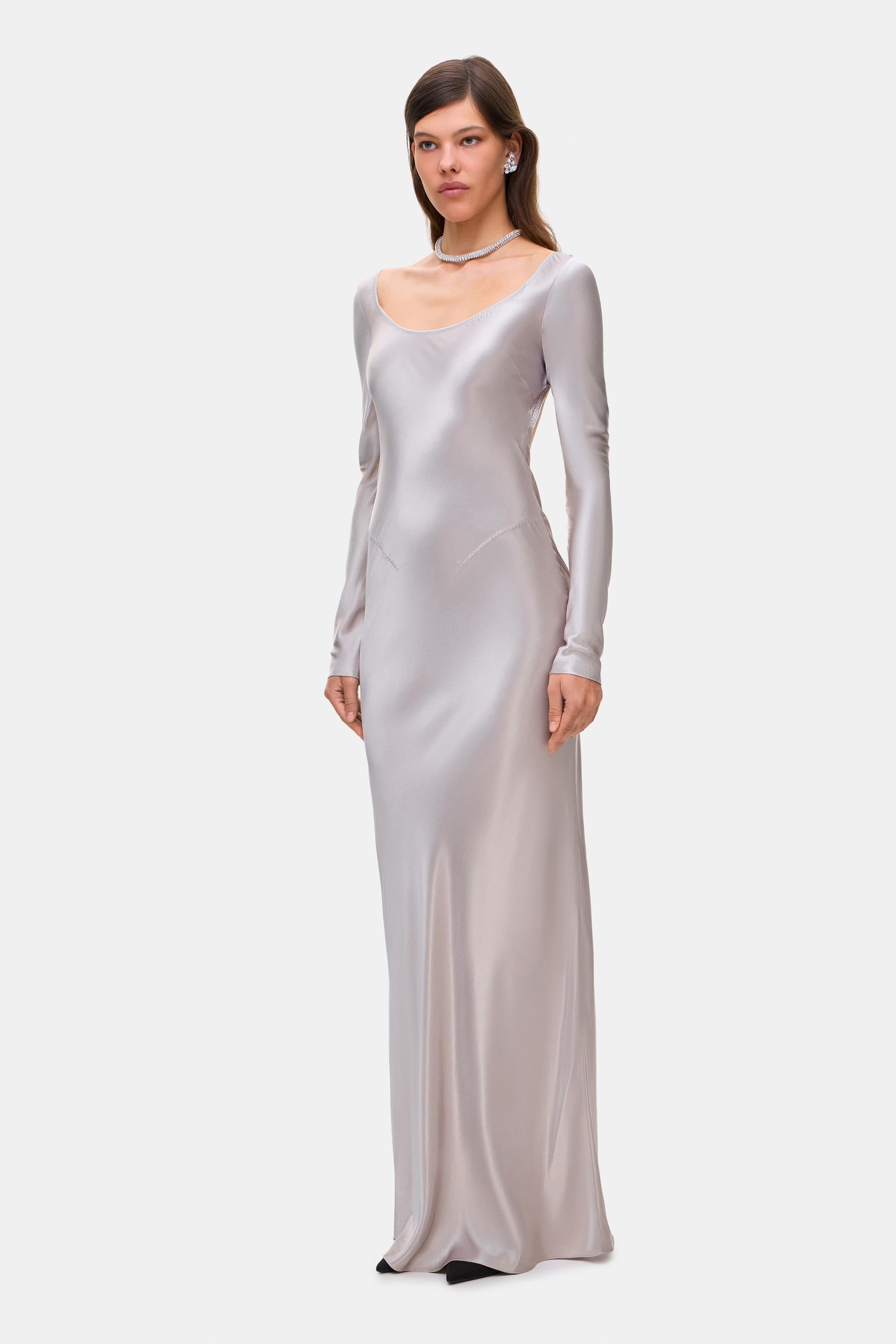 Woman wearing a silver long-sleeve Margit dress on a white background, side view