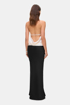 Woman wearing a two-tone Ayla dress with a white top and black skirt on a white background, back view