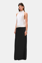 Woman wearing a two-tone Ayla dress with a white top and black skirt on a white background, side view