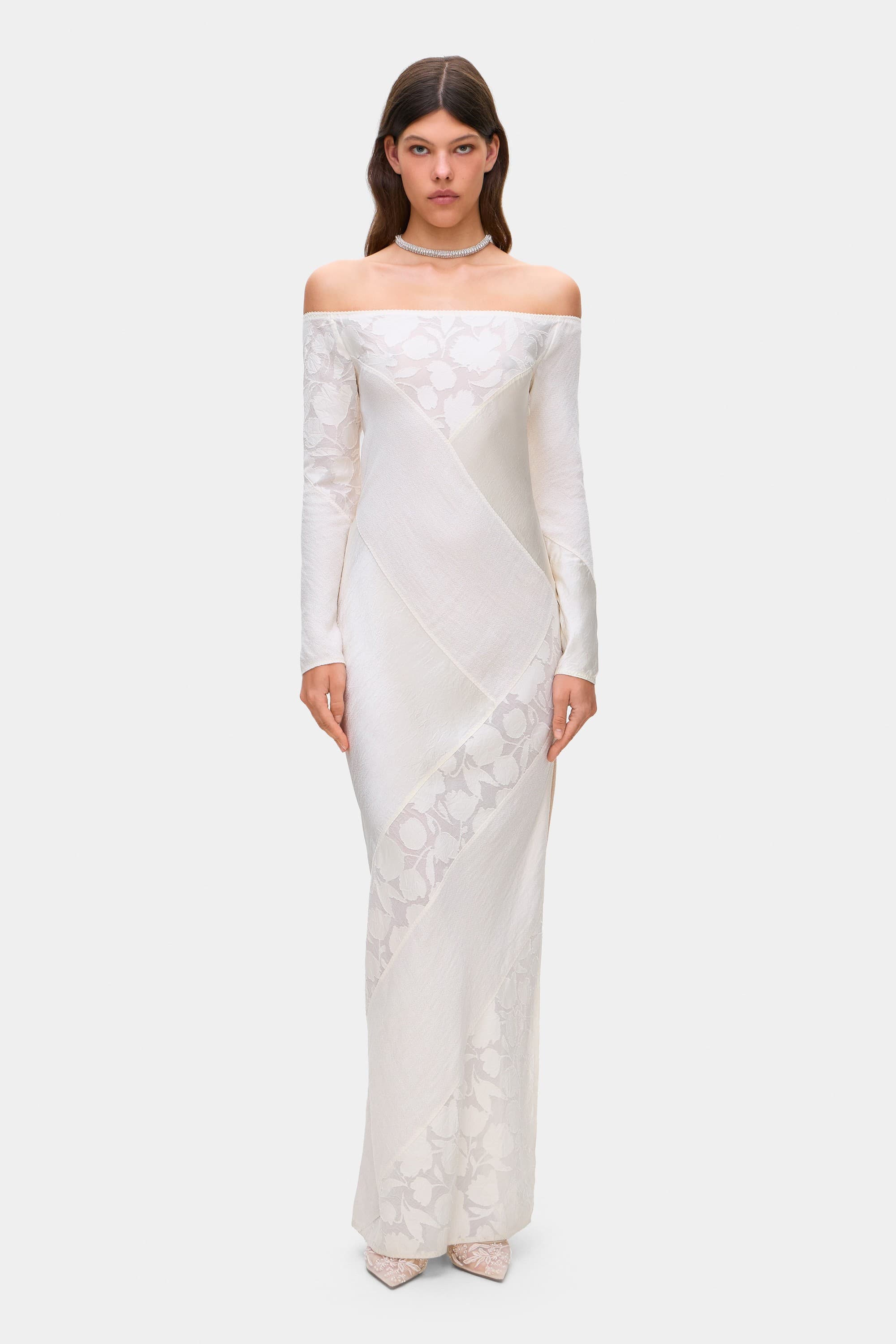 Woman wearing a ivory long-sleeve off-shoulder Santa dress with floral patterns on a white background, front view