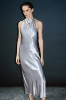 Woman wearing a silver halter neck Jordana dress against a dark background
