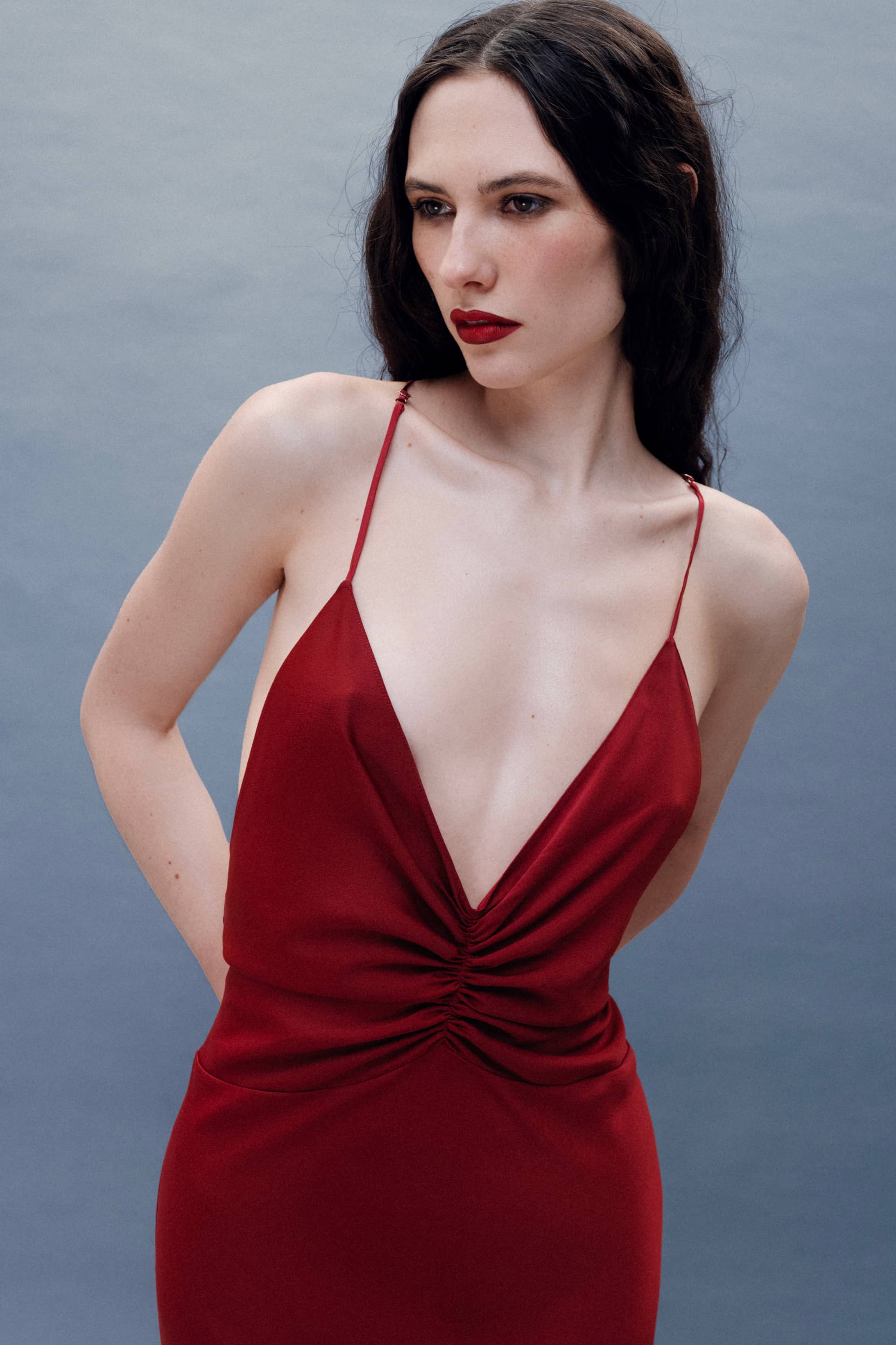 Woman wearing a red Maltina dress against a gray background