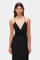 Woman wearing a black Eliana dress on a white background, front details view