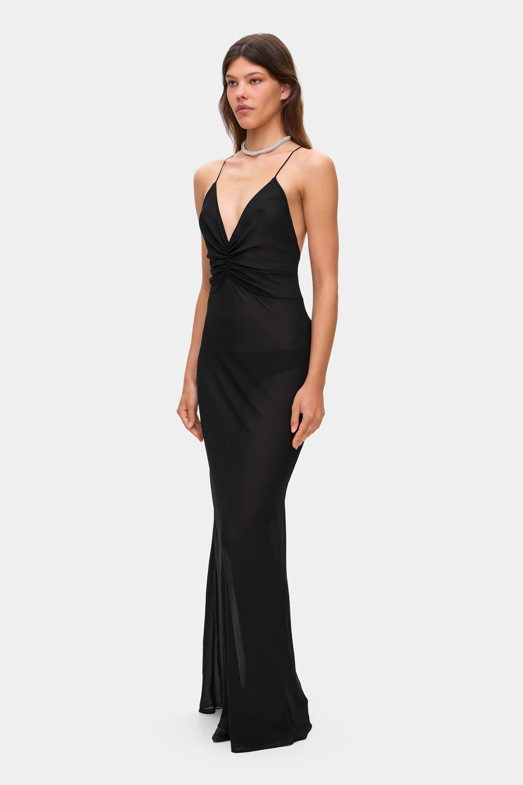 Woman wearing a black Eliana dress on a white background, side view
