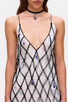 Woman wearing a ivory and black netted patterned with thin straps  Helena dress on a white background, front details view