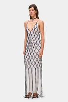 Woman wearing a ivory and black netted patterned with thin straps  Helena dress on a white background, side view