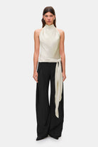 Woman wearing a ivory sleeveless Soma top and black wide-leg pants, front view