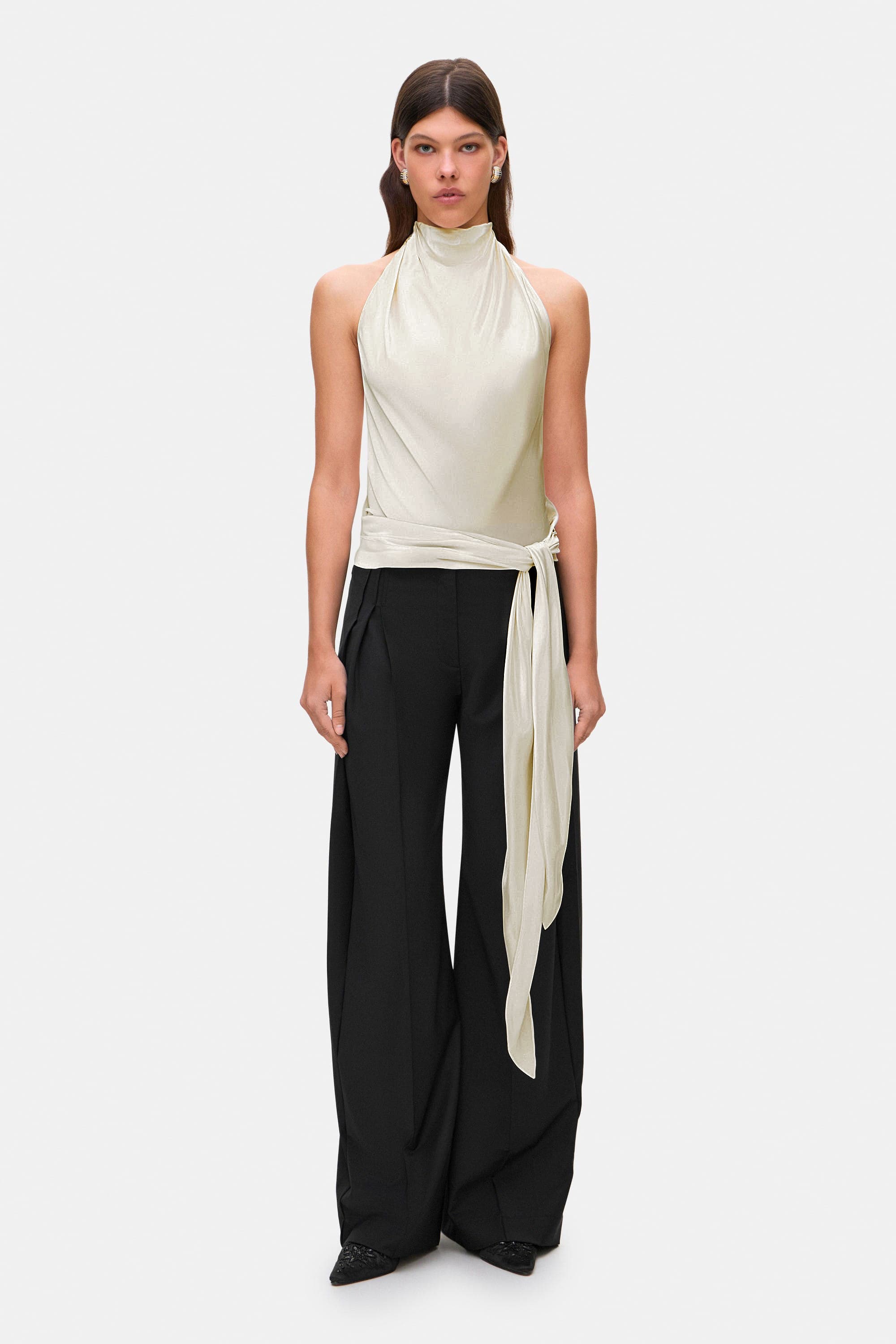 Woman wearing a ivory sleeveless Soma top and black wide-leg pants, front view