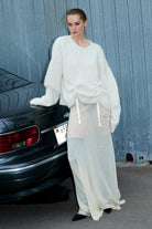 Woman in a ivory Cleo sweater outfit standing next to a car with a textured wall background