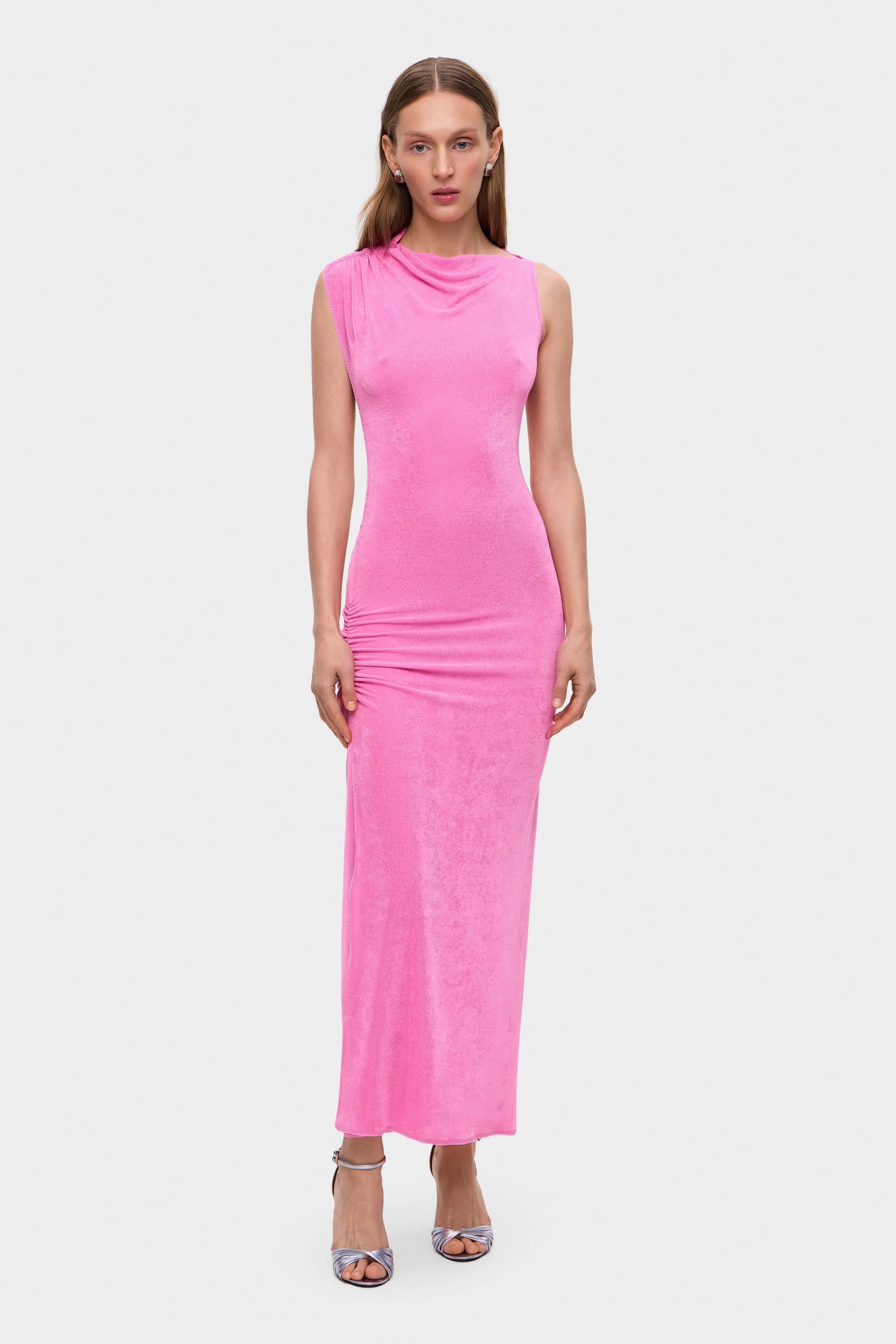 Woman wearing a pink sleeveless Aya dress with cut-out design on a white background, front view